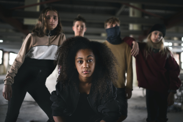 Front view of group of teenagers gang standing indoors in abandoned building, bullying concept.