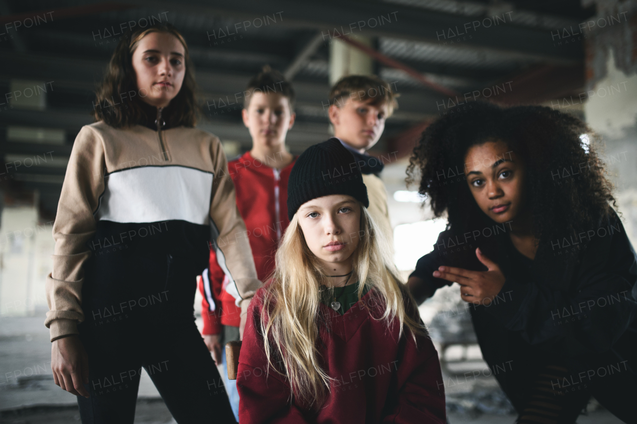 Front view of group of teenagers gang standing indoors in abandoned building, bullying concept.