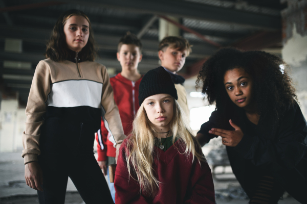 Front view of group of teenagers gang standing indoors in abandoned building, bullying concept.