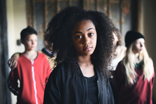 Front view portrait of mixed- race teenager girl with friends standing indoors in abandoned building.