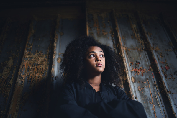 Front view portrait of mixed- race teenager girl standing indoors in abandoned building.