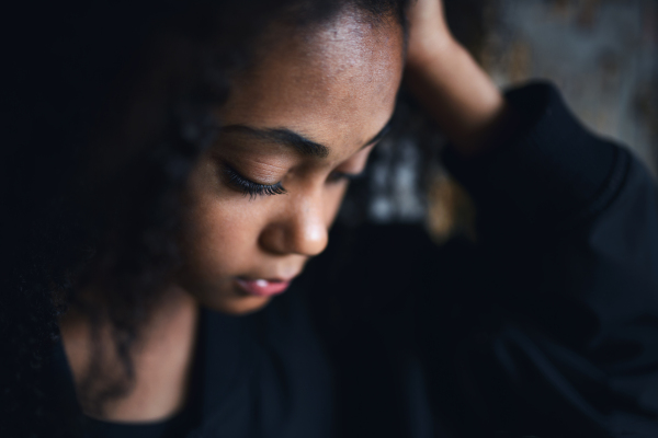 A close-up portrait of sad mixed-race teenager girl standing, bullying concept.