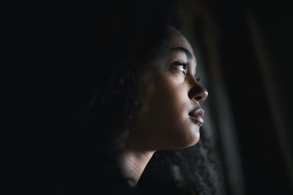 A close-up portrait of sad mixed-race teenager girl standing, bullying concept.