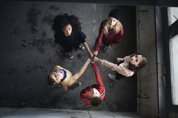 A top view of group of teenagers gang standing indoors in abandoned building, looking at camera.