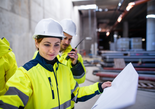 A group of male and female engineers standing on construction site, working.