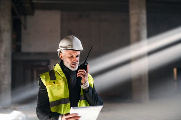 Man engineer using walkie talkie indoors on construction site.