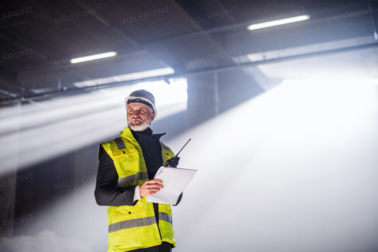 Man engineer using walkie talkie indoors on construction site.