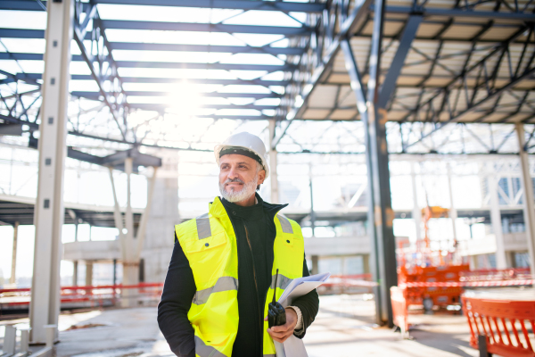 Front view of man engineer with walkie talkie standing on construction site.