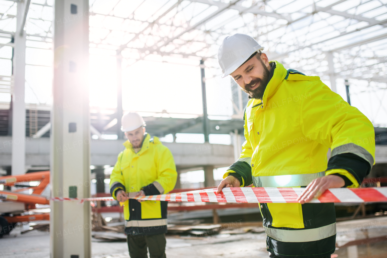 Men workers standing outdoors on construction site, working in winter.