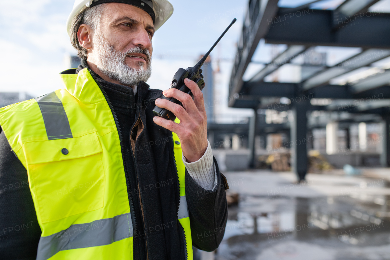 Man engineer using walkie talkie outdoors on construction site.