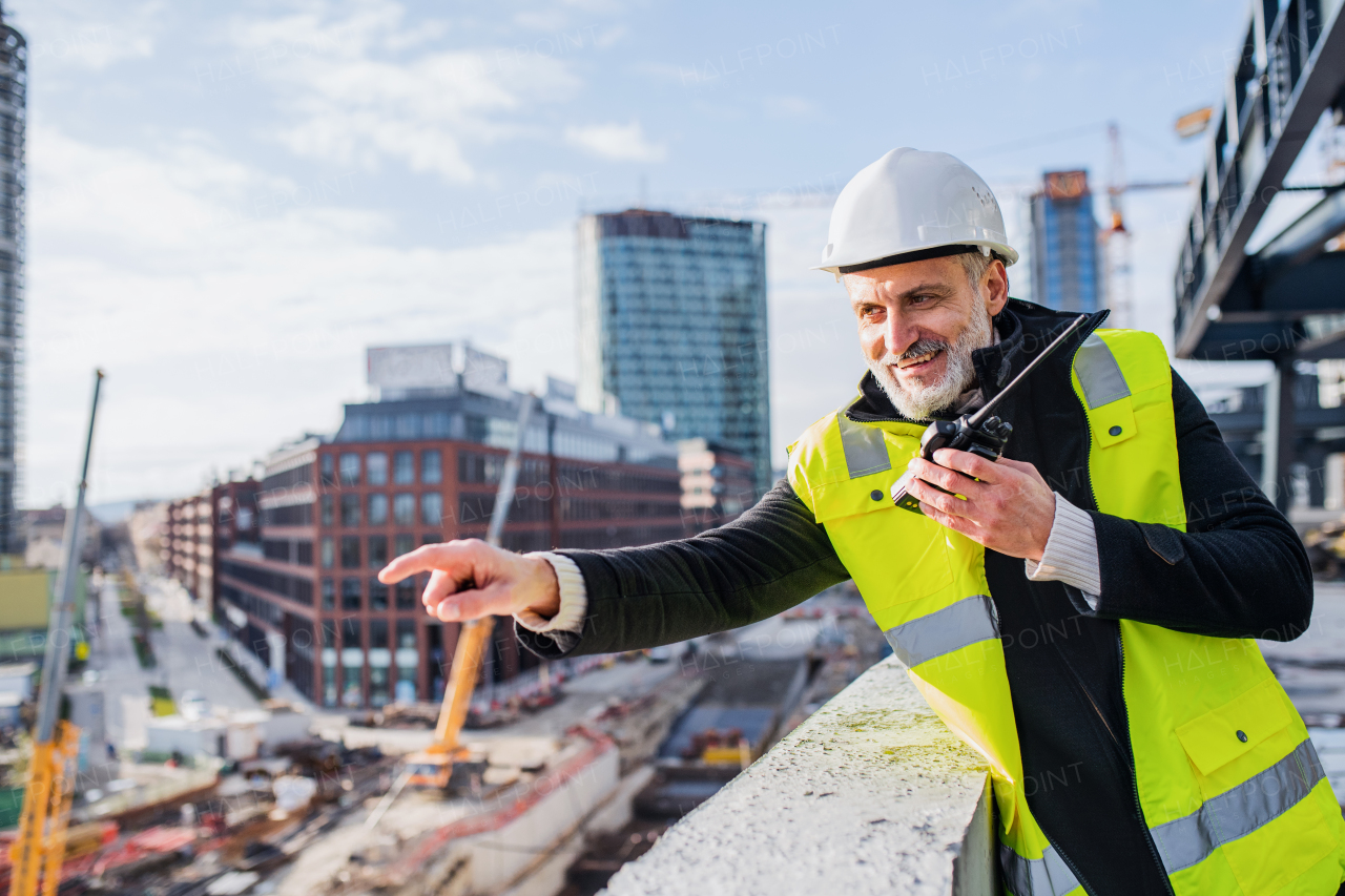 Man engineer using walkie talkie outdoors on construction site.