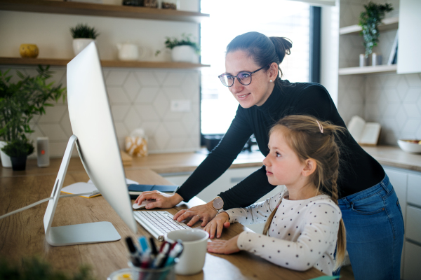 Woman with small daughter working indoors at home office, Corona virus and quarantine concept.