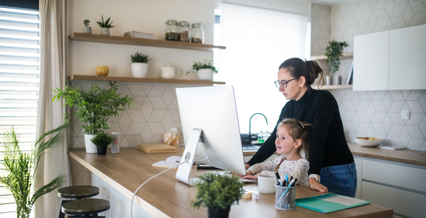 Woman with small daughter working indoors at home office, Corona virus and quarantine concept.