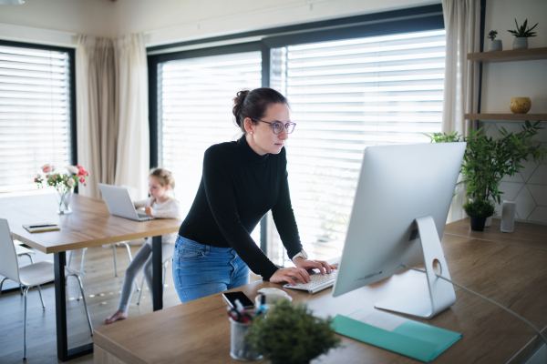 Woman with daughter working indoors at home office, Corona virus and quarantine concept.