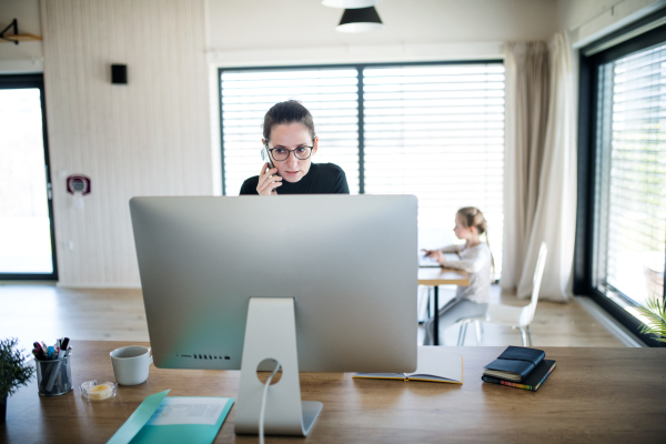 Woman with daughter working indoors at home office, Corona virus and quarantine concept.