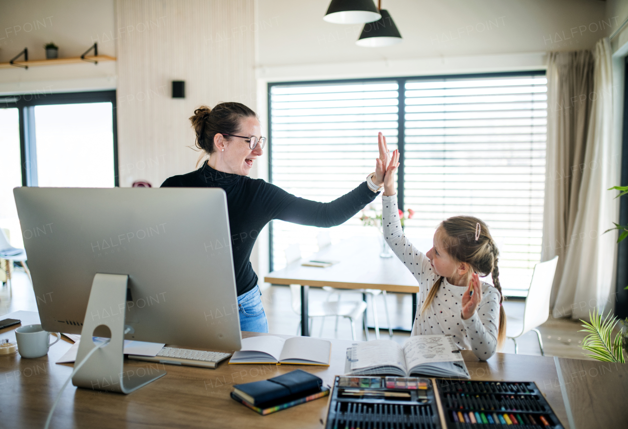 Woman with small daughter working indoors at home office, Corona virus and quarantine concept.