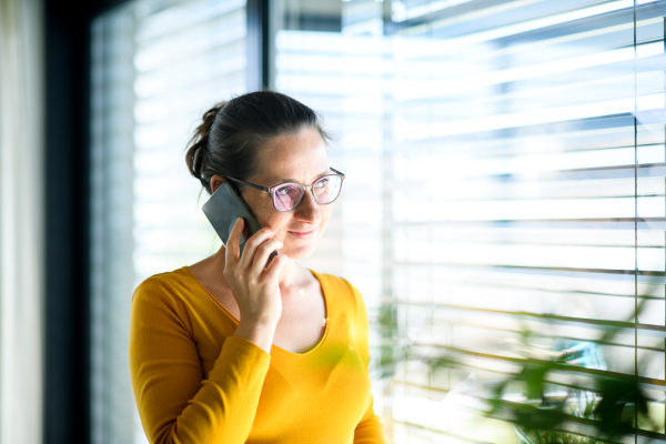 Woman with smartphone working indoors at home office, Corona virus and quarantine concept.