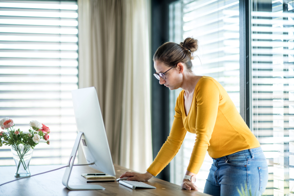 Woman with face mask working indoors at home office, Corona virus and quarantine concept.