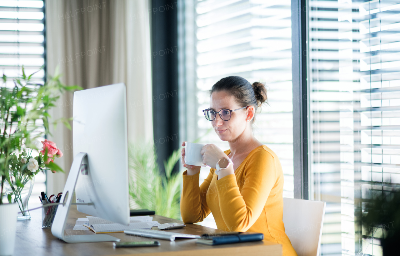 Woman with coffee working indoors at home office, Corona virus and quarantine concept.