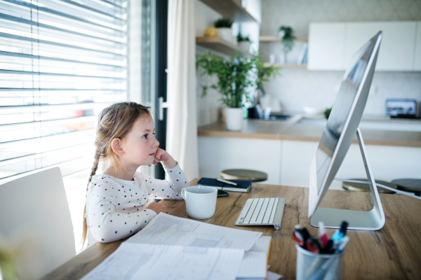 Small girl watching story on computer indoors at home office, Corona virus and quarantine concept.