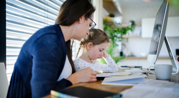 Mother and small daughter learning indoors at home, Corona virus and quarantine concept.