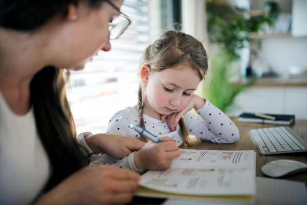 Mother and small daughter learning indoors at home, Corona virus and quarantine concept.