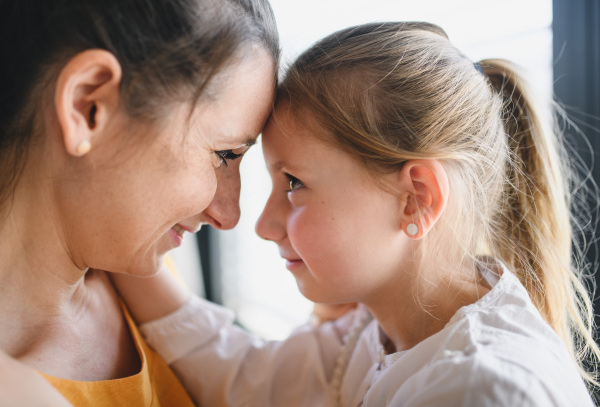 Side view of mother and child indoors at home, hugging.