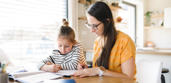 Mother and small daughter learning indoors at home, Corona virus and quarantine concept.