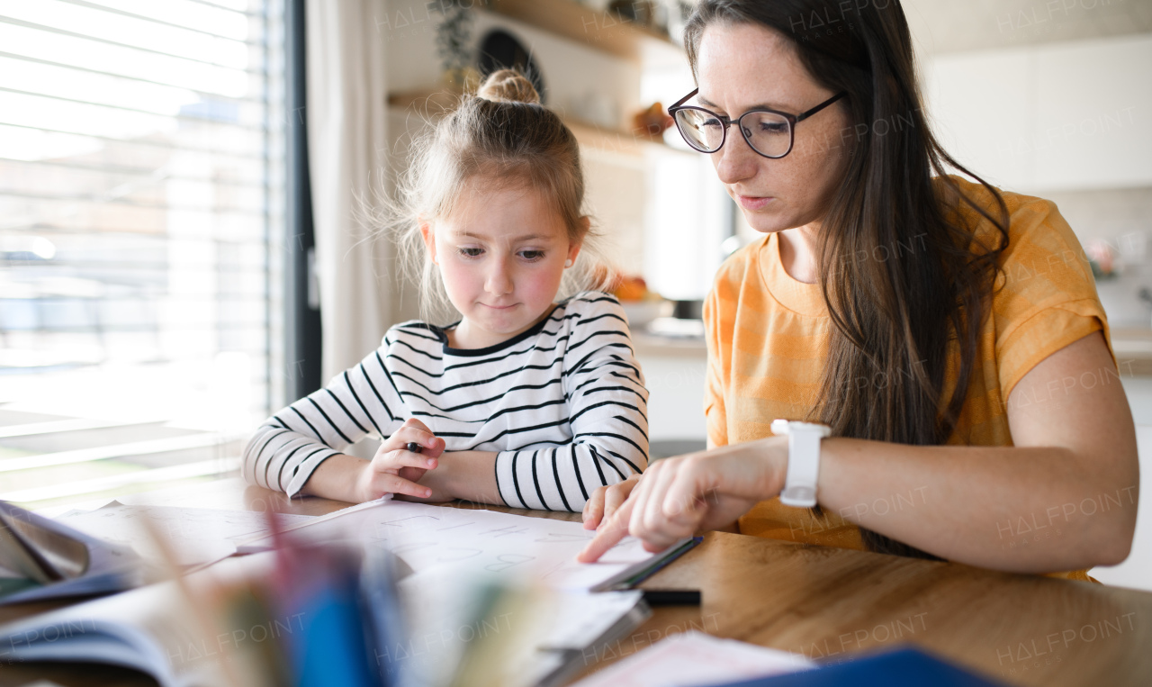 Mother and small daughter learning indoors at home, Corona virus and quarantine concept.