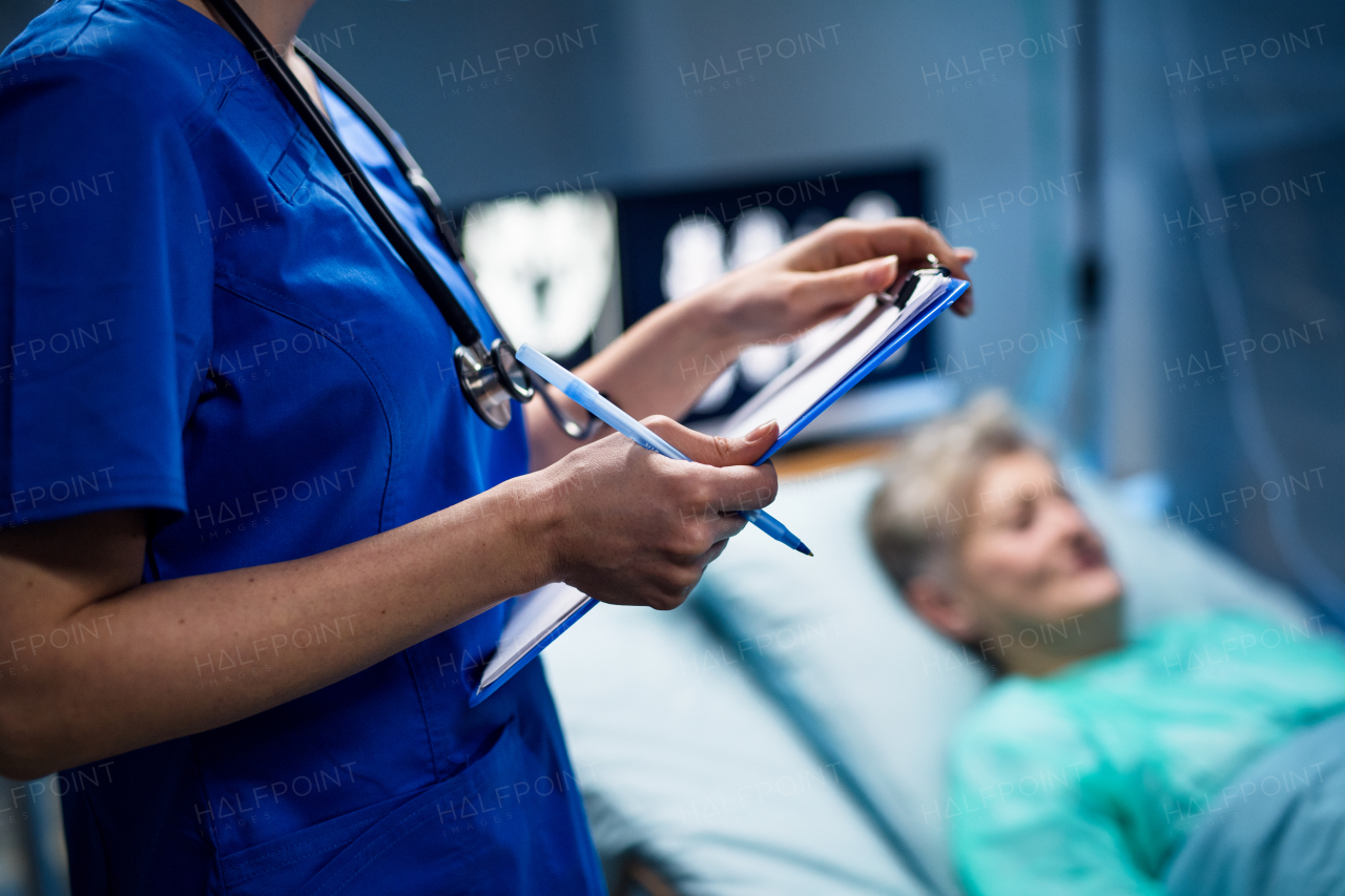 A midsection of doctor with clipboard in hospital, coronavirus concept.