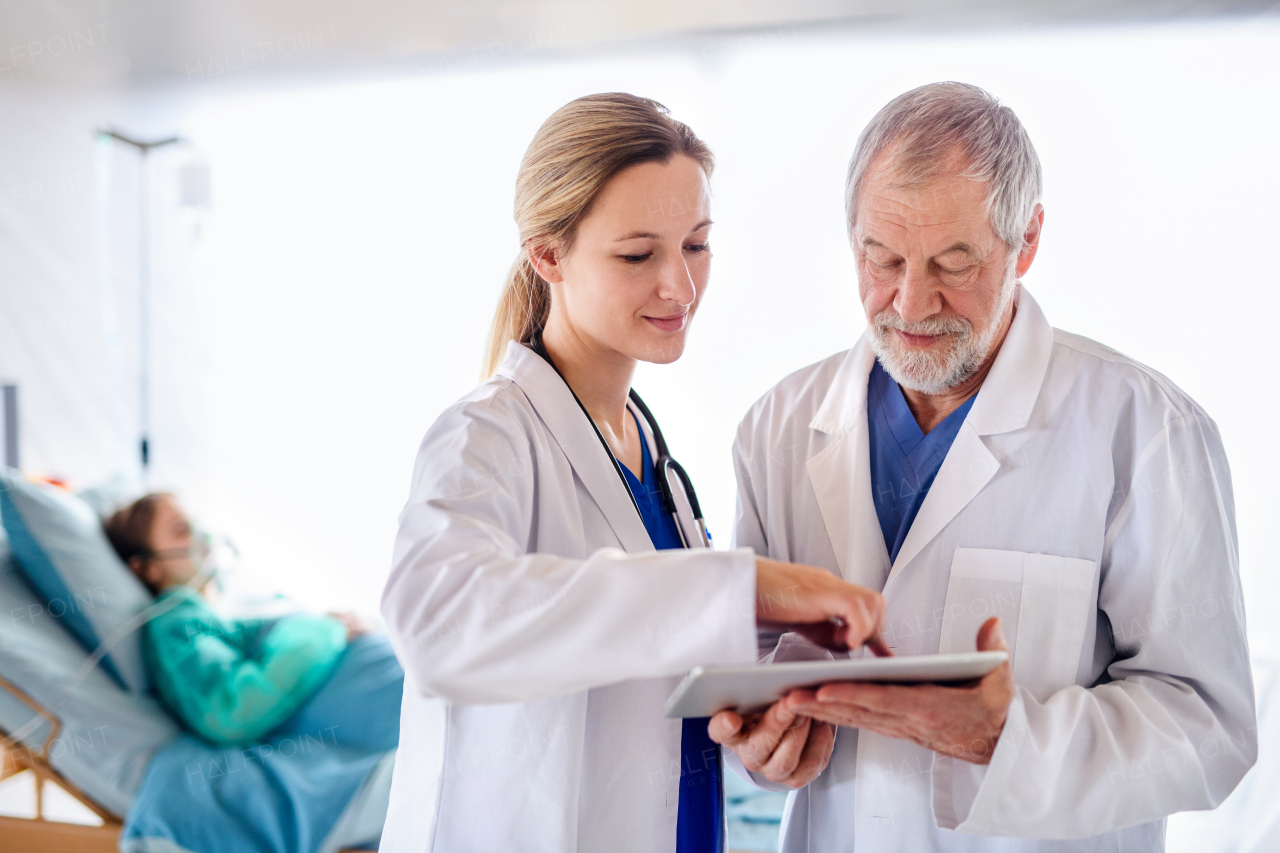 Man and woman doctors with tablet talking in hospital, coronavirus concept.