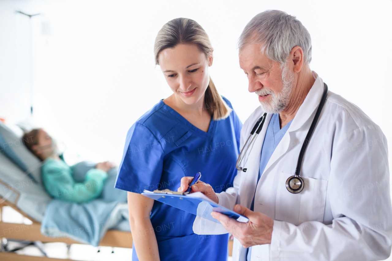 Man and woman doctors with clipboard talking in hospital, coronavirus concept.