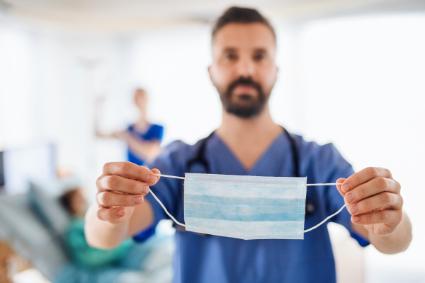 Portrait of doctor holding face mask in hospital, coronavirus concept.