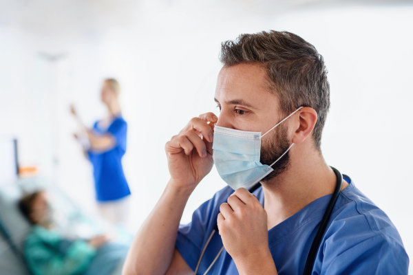 Side view of doctor with face mask in hospital, coronavirus concept. Copy space.