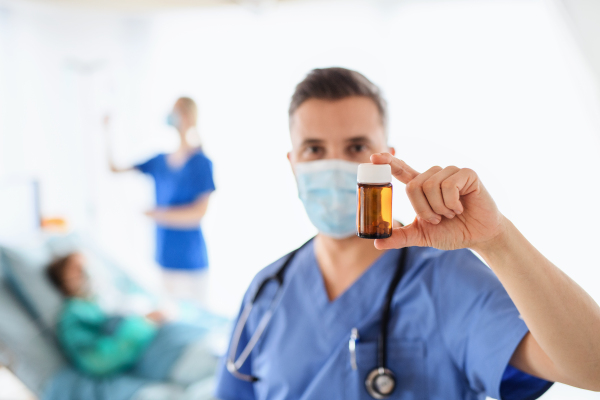 Portrait of doctor holding medication cure in hospital, coronavirus concept.