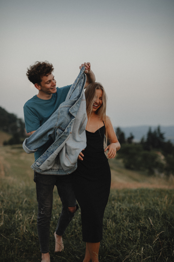 Front view of young couple walking in nature in countryside, laughing.