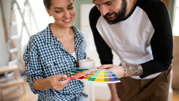 Front view of mid adults couple with colour swatch indoors at home, relocation and diy concept.