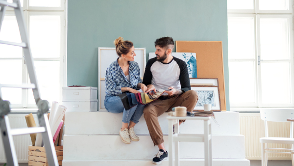 Front view of mid adults couple with colour swatch indoors at home, relocation and diy concept.