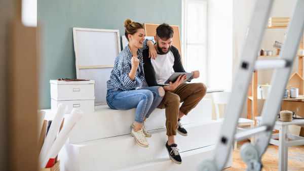 Front view of mid adults couple planning with tablet indoors at home, relocation and diy concept.