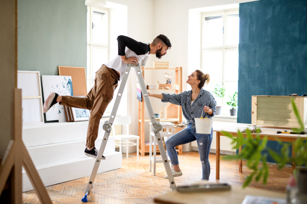 Happy mid adults couple having fun when painting indoors at home, relocation and diy concept.