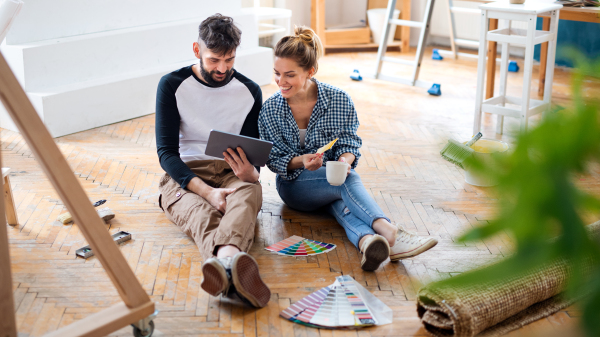 Front view of mid adults couple planning with tablet indoors at home, relocation and diy concept.