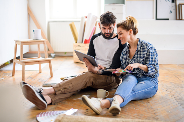 Front view of mid adults couple planning with tablet indoors at home, relocation and diy concept.