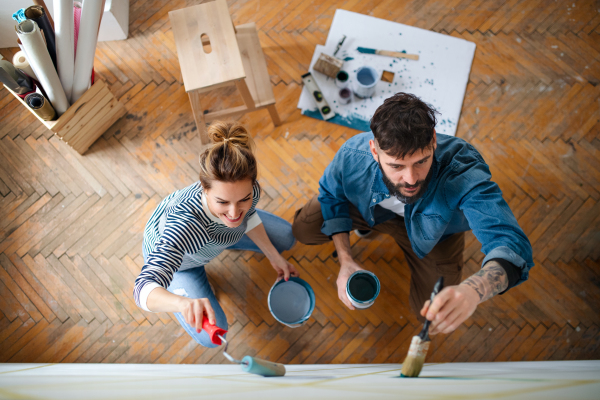 Top view of mid adults couple painting wall indoors at home, relocation and diy concept.