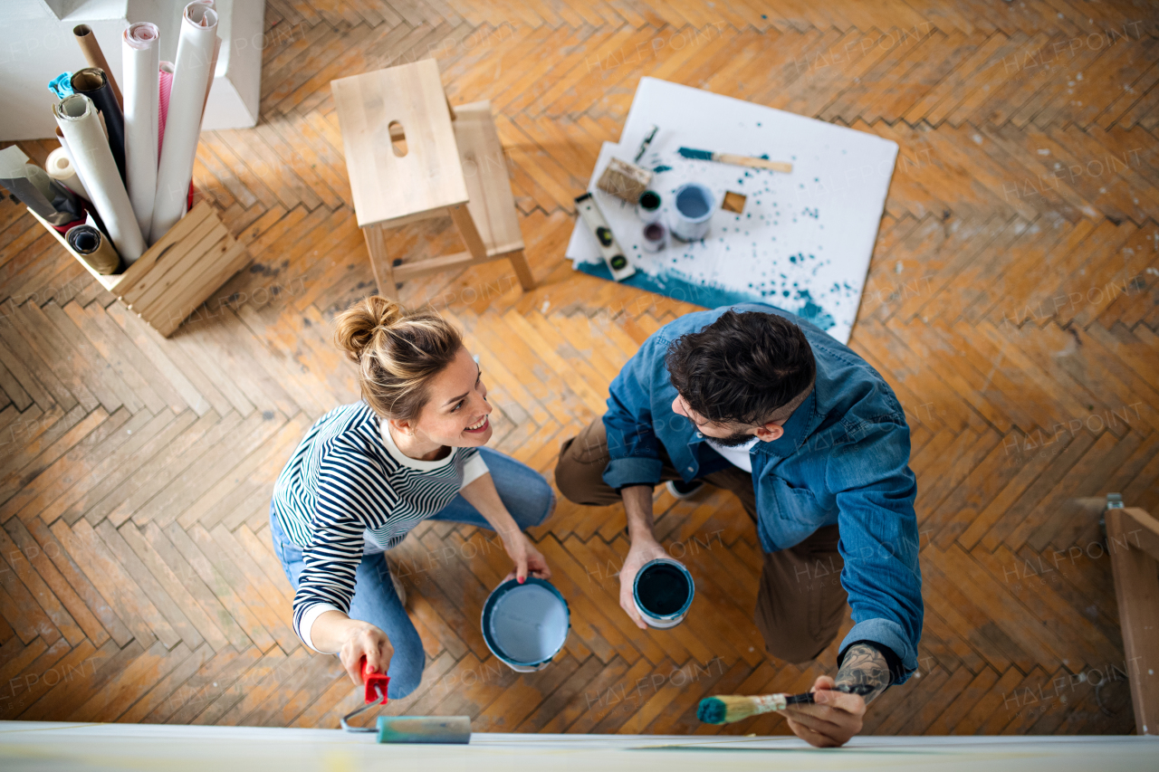 Top view of mid adults couple painting wall indoors at home, relocation and diy concept.