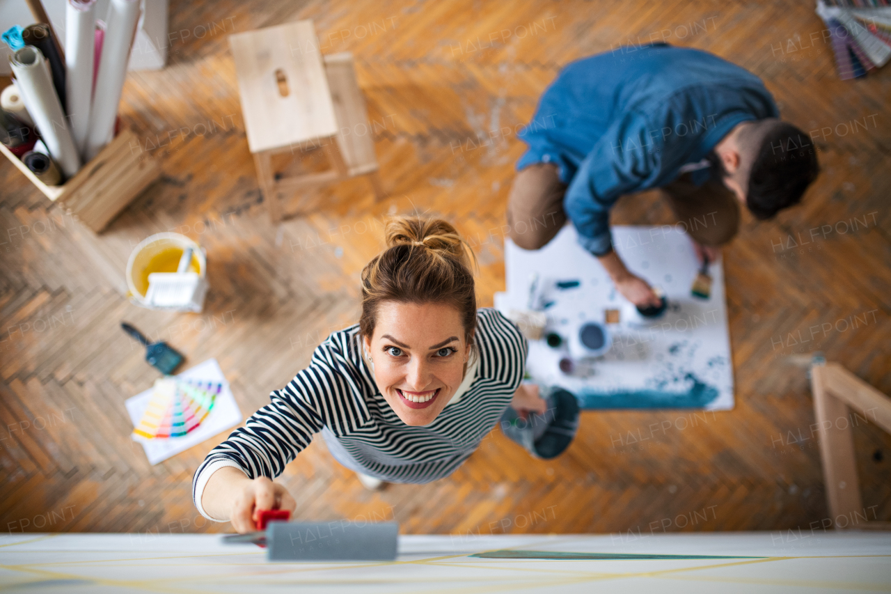 Top view of mid adults couple painting wall indoors at home, relocation and diy concept.