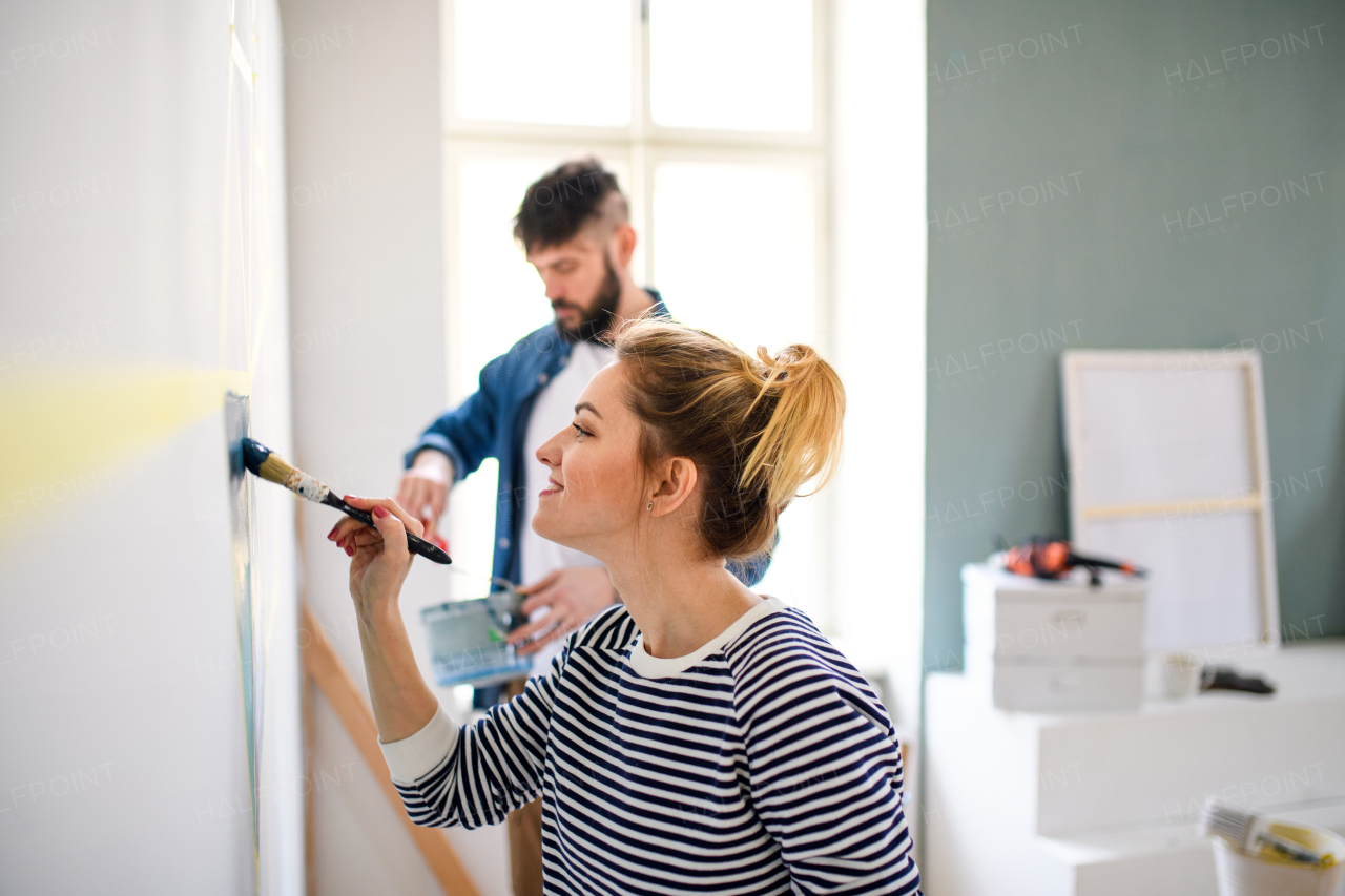 Happy mid adults couple painting wall indoors at home, relocation and diy concept.