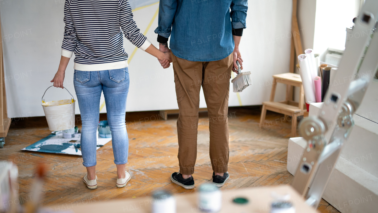 Unrecognizable mid adults couple painting wall indoors at home, relocation and diy concept.