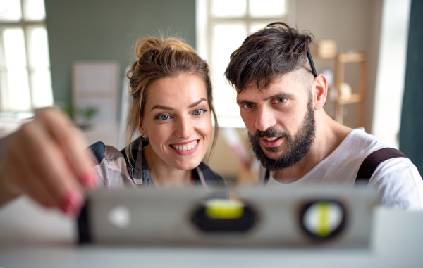 Happy mid adults couple with leveler indoors at home, relocation and diy concept.