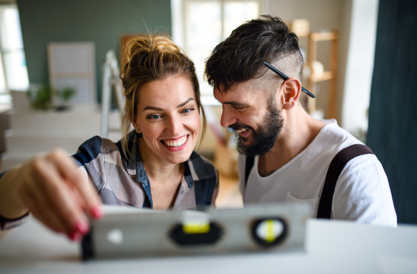 Happy mid adults couple with leveler indoors at home, relocation and diy concept.