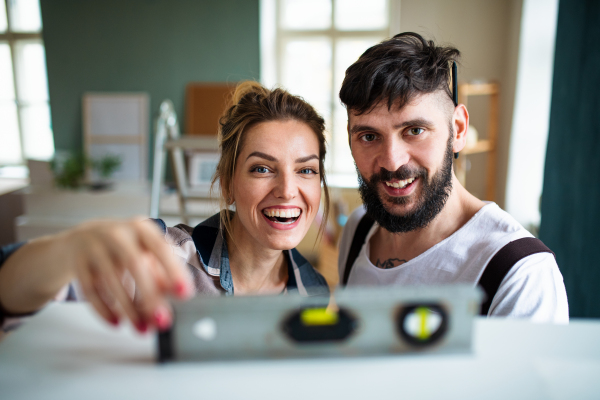 Happy mid adults couple with leveler indoors at home, relocation and diy concept.